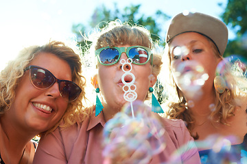 Image showing Women, friends and bubbles for blowing outdoor with sunglasses on weekend, break or holiday for relax and summer. People, happy and plastic wand or toy for playing or leisure on vacation or adventure