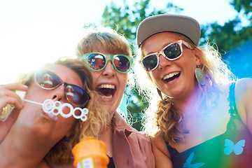 Image showing Women, friends and bubbles for blowing or fun outdoor with sunglasses on weekend, break and holiday for relax. People, happy and plastic wand or toy for playing or laughing with vacation or adventure