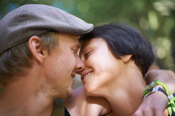 Image showing Couple, closeup and embrace outdoors for date with wristband for festival, concert or adventure together. Man, woman and smile with flat cap for summer in nature, forest or woods with happiness