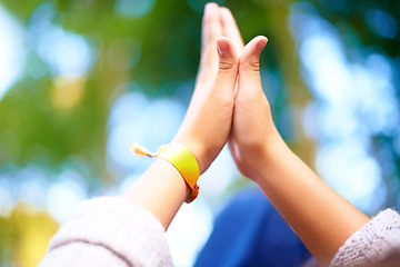 Image showing Outdoor, closeup and people with high five, nature and agreement with bokeh background or fresh air. Fun, closeup or friends with hand gesture or support with party or event with motivation or ribbon