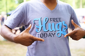 Image showing Tshirt, outdoor and man with fun, pointing and free hugs today with party and promotion. Motivational slogan, person and guy with casual outfit and stylish clothes with sunshine and summer break