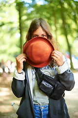 Image showing Portrait, hat and woman at music festival, outdoor and peeking at event in summer. Face, fashion and girl hide behind fedora for style, shy and casual young person alone at party in France in nature