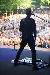 Image showing Singer, music festival and man with performance, back and outdoor for event and crowd with celebration. Person, party and artist with microphone and audience with sunshine and fans screaming with fun