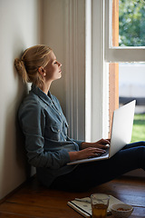 Image showing Woman, freelancer and laptop by window, writer and internet connection on floor for info. Female person, editor and website for research or online news, blogging and typing an article on technology