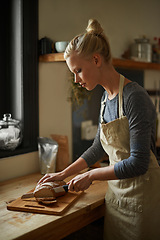 Image showing Bakery, kitchen and woman with knife on bread, cutting on board and cooking gluten free food for breakfast. Fresh, loaf and chef in restaurant with healthy rye in preparation process of brunch