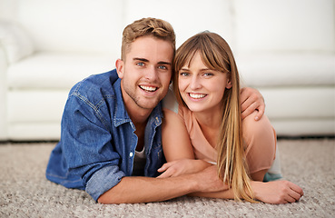 Image showing Happy, portrait and couple lay on carpet of living room in house to relax, bonding and romance for love. Man, woman and together on rug in lounge of home with affection, care and hug for connection