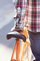 Image showing Hands, person and travel on bicycle in city on eco friendly transport outdoor, commute or walk. Cycling, back or push bike in urban town, street or road for journey with rear view of seat on sidewalk