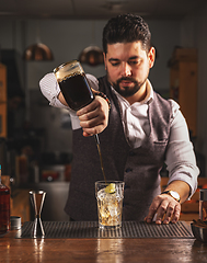 Image showing Bartender pouring craft cocktail at bar