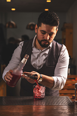 Image showing Expert bartender pouring cocktail at bar