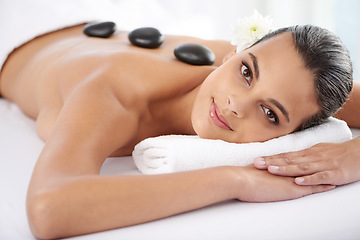 Image showing Smile, hot stone and portrait of woman with massage at spa for wellness, health and back treatment. Self care, cosmetic and young female person relaxing for warm rock therapy at natural beauty salon.