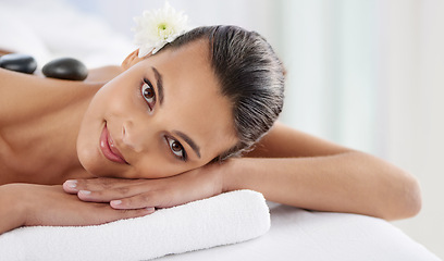 Image showing Portrait, hot stone and woman laying for massage at spa for wellness, health and back treatment. Self care, cosmetic and young female person relaxing for warm rock therapy at natural beauty salon.