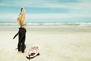 Image showing Sports, stretching and woman on beach with surfboard for travel, vacation or holiday on tropical coast. Earth, nature and sky with surfer on sand by sea or ocean for hobby or leisure from back
