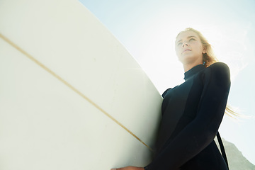 Image showing Face, flare and woman on beach with surfboard from below for travel, vacation or adventure on coast in summer. Nature, fitness or exercise with confident young surfer person in wetsuit for recreation
