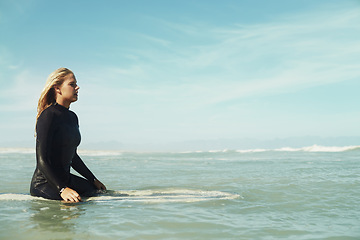 Image showing Sports, space and woman in ocean on surfboard to relax with sports, fitness or exercise in summer. Nature, sea and wave with confident young surfer person on blue sky for vacation, holiday or balance
