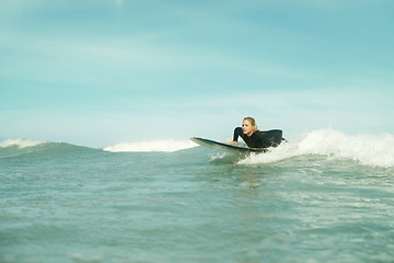 Image showing Summer, sports and woman on surfboard in sea with space for outdoor travel, vacation or holiday. Ocean, wave and splash with young surfer person outdoor on blue sky for fitness, exercise or training