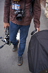 Image showing Lighting, equipment and photographer in outdoor for photoshoot with camera lens and gear. Cameraman, walking and photography tools for press, project and person travel on street with reflector tech