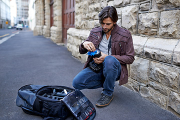 Image showing Clean, camera lens and photographer work with equipment outdoor and prepare for photoshoot in city. Cameraman, wipe and start project with gear for photography on town street for professional media