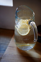 Image showing Water, lemon and jug in kitchen for health benefits or detox drink for hydration or natural vitamins, organic or counter. Beverage, fruit and glass in home for antioxidants, vitamin c or immunity