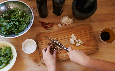 Image showing Hands, chopping and ingredients in kitchen for salad preparation or walnuts, leafy greens or garlic. Person, knife and cooking vegan meal on wooden board with spices for nutrition, health or top view