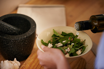 Image showing Salad, olive oil and hand with bowl for healthy food, eating meal of leaves or lettuce with cheese in kitchen. Person cooking, hungry and preparing dish with ingredients, vegetables and dressing