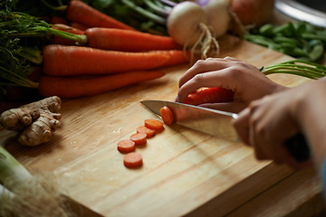 Image showing Vegetables, hands and person with knife and carrot cut and for cooking lunch and nutrition diet at home. Wellness, health and organic food with meal, vegetarian and ingredients for salad in a kitchen