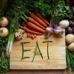 Image showing Food, chopping board and message for eating, nutrition and cooking for wellbeing or love. Home, wellness and vegetables for diet, health and vitamins in kitchen for vegan, vitality and still life