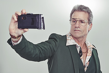 Image showing Mature man, fashion and selfie with camera in photography, memory or cool style on a gray studio background. Senior, male person with glasses and posing for photo, picture or trend in formal clothing