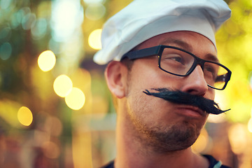 Image showing Man, fake mustache and beret in chef costume with comic face, creative and confident in french baking. Young person, glasses and cooking job in bokeh and culinary education in pastry art in europe