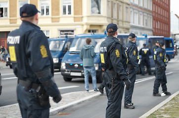 Image showing Police officer, group and patrol in street for crowd safety with protection service for public in city. People, law enforcement and justice in danger, arrest or warning on urban road in Copenhagen