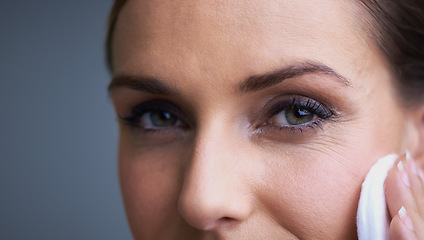 Image showing Woman, eyes and pad for makeup, beauty or removal in anti aging or cosmetics on a gray studio background. Closeup of female person wiping face with cotton in satisfaction for collagen or cleaning