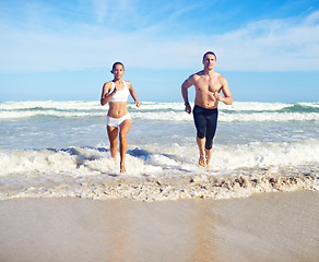 Image showing Running, beach and couple with fitness, waves and weekend break with cardio and training for health. Runners, seaside and man with woman and support with practice and activity for wellness and hobby