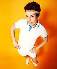 Image showing Studio, portrait and man in retro tennis uniform with confidence, smile and high angle. Gym, club and happy athlete in vintage sports fashion on orange background with pride, game and sportswear.