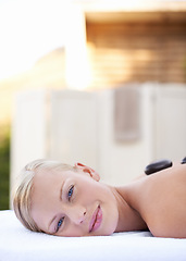 Image showing Spa, woman and hot stone on massage bed with portrait for wellness, mockup and beauty treatment for body care. Person, face and stress relief at resort, salon table and relax on holiday or vacation