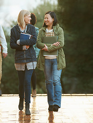 Image showing Students, women and friends on campus for college, conversation while walking to class and smile. University, communication and books for studying, education and academic growth with talk outdoor