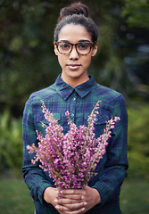 Image showing Woman, flower bouquet and portrait in garden, nature and blossom with environment, relax in Spring with gift outdoor. Purple plant, present and botanical with sustainability and romantic gesture