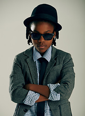 Image showing Sunglasses, fashion and kid with arms crossed in studio for stylish suit isolated on a grey background. Face, confidence and serious African child in hat, cool or black boy in trendy clothes in Kenya