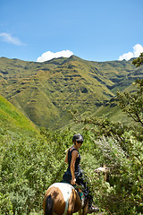 Image showing Woman, mountains and horse riding for outdoor adventure, travel and journey with sustainability or tourism. Portrait of an equestrian or horseback rider on a hill in nature for holiday and vacation