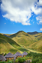 Image showing Landscape, valley and hills with blue sky in Lesotho for travel, holiday or vacation in summer. Housing, huts or shelter in nature for rural accommodation in scenic environment of green mountains