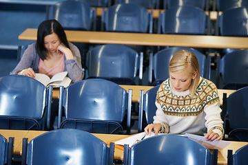 Image showing University, students and writing notes in lecture, hall and learning in class with education. College, campus and people studying for test in school and reading project, research or knowledge