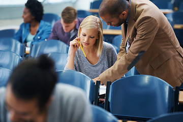 Image showing University, helping and professor with student in classroom studying for test, exam or assignment. Education, learning and teacher talking and explaining college information to woman in lecture hall.