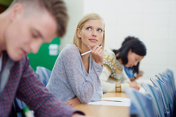 Image showing Student, thinking and exam writing in university classroom for education assessment for learning, answer or scholarship. Female person, pencil and thoughts in lecture hall or idea, school or London