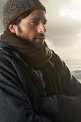 Image showing Man, nature and winter fashion by ocean for cold, comfort and protection in cape town weather climate. English guy, idea and trendy clothes of scarf, beanie and thinking at overcast beach in morning