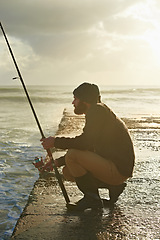 Image showing Man, waiting and fishing on beach in nature, relax and natural sea hobby for wellness on vacation. Fisherman, travel or holiday in cape town by ocean, adventure or patient by hook for fish to bite