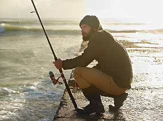 Image showing Man, thinking and fishing on beach in hobby, relax and sea for peace wellness on holiday. Fisherman, natural and vacation in cape town by ocean, adventure and nature by hook for fish to bite