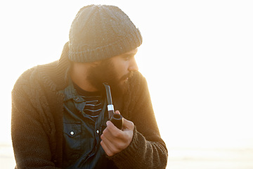 Image showing Holiday, man and smoking a pipe on beach, thinking and sunrise with tobacco habit in winter. English guy, nicotine addiction or vintage smoker for calm, satisfaction or vacation by ocean in cape town