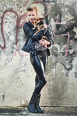 Image showing Dog, portrait and woman in leather clothes by graffiti wall, confident and bonding with chihuahua in city. London, designer or face for fashion in town, vacation or care for pet animal by street art