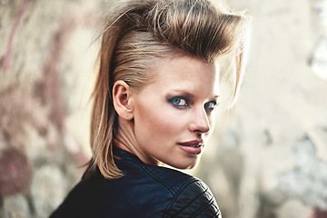 Image showing Woman, portrait and happy in edgy fashion with punk rock hairstyle, attitude and cool in funky clothes by wall. Person, face and leather jacket in urban town, unique and trendy with confidence