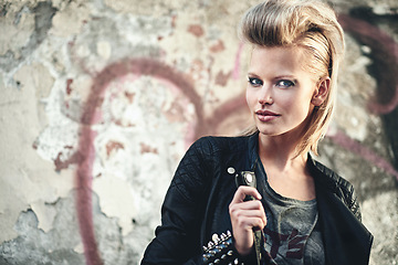 Image showing Woman, portrait or cosmetics in edgy fashion with punk rock hairstyle, attitude or cool in funky clothes by graffiti wall. Artist, face and leather jacket in urban town and trendy style by street art