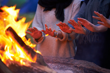 Image showing Hands, fire and people camping outdoor, keeping warm with open flame at campsite, friends huddle for heat and bonding. Travel, nature and relax around campfire, community and together for adventure