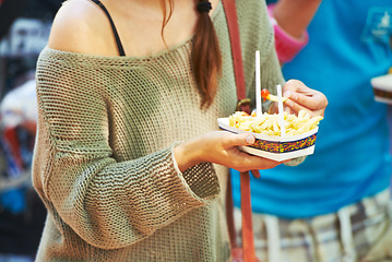Image showing Hands, person and eating french fries outdoor, delicious snack and tasty cuisine for nutrition in summer. Fast food, chips and hungry for unhealthy lunch, junk and fresh crispy potato meal for diet